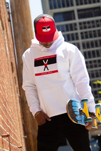 Man wearing white hoodie with black white and red Heart-OMS flag on center front. Man holding skateboard wearing black and red flat bill cap with heart-oms flag on the front.