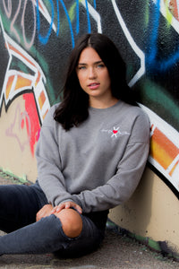 Woman wearing grey cotton crop sweatshirt with white HOMS logo and symbol in cursive on left chest