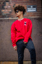 Load image into Gallery viewer, man in red sweatshirt with black and white Heart-OMS symbol embroidered on the left front chest.